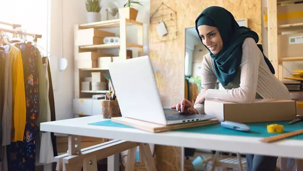 An ecommerce business owner checks an order on her laptop.